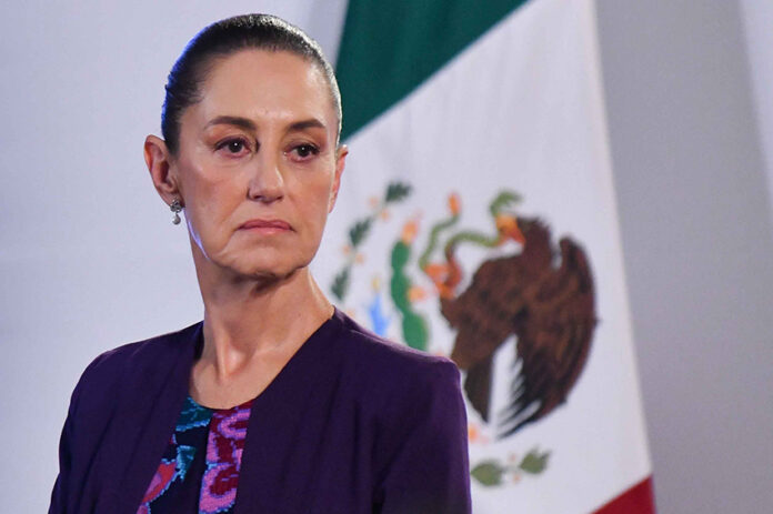 Claudia Sheinbaum with a serious expression and a Mexican flag