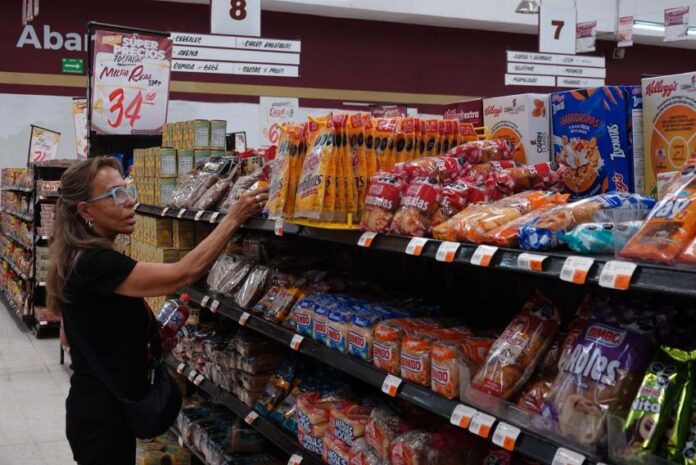 A woman takes a product off a grocery store shelf