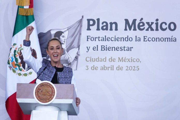 Mexico's President Claudia Sheinbaum stands at the presidential podium looking out at an audience off-camera with her fist raised and her mouth open as if cheering. Behind her is a wall with the words in Spanish: Plan Mexico, Strenghtening the Economy and Well-Being, Mexico City April 3, 2025.