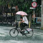 A man with an umbrella rides a bicycle in the rain in Mexico City