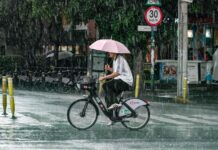 A man with an umbrella rides a bicycle in the rain in Mexico City