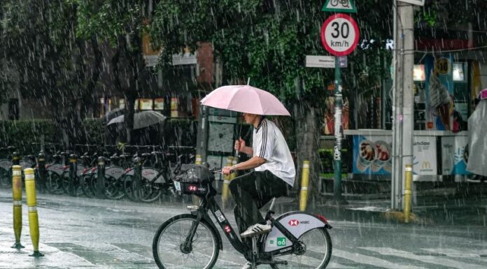 A man with an umbrella rides a bicycle in the rain in Mexico City