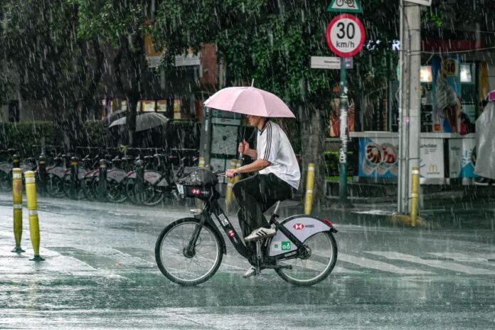 A man with an umbrella rides a bicycle in the rain in Mexico City