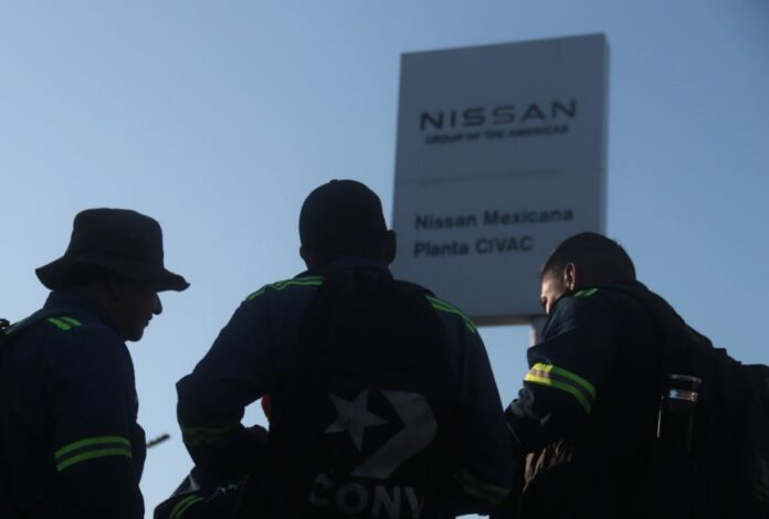 silhouetted figure in front of a Nissan sign