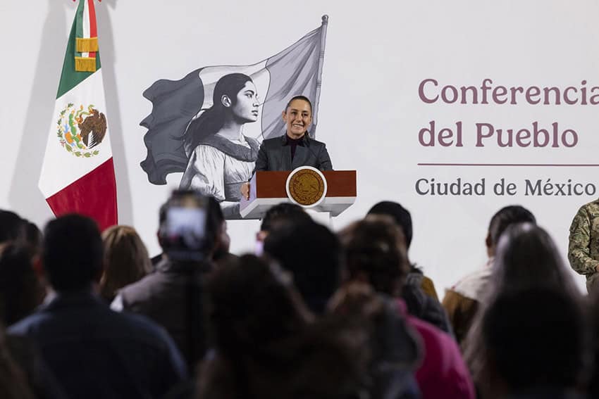 Sheinbaum stands at a podium in front of an audience of reporters