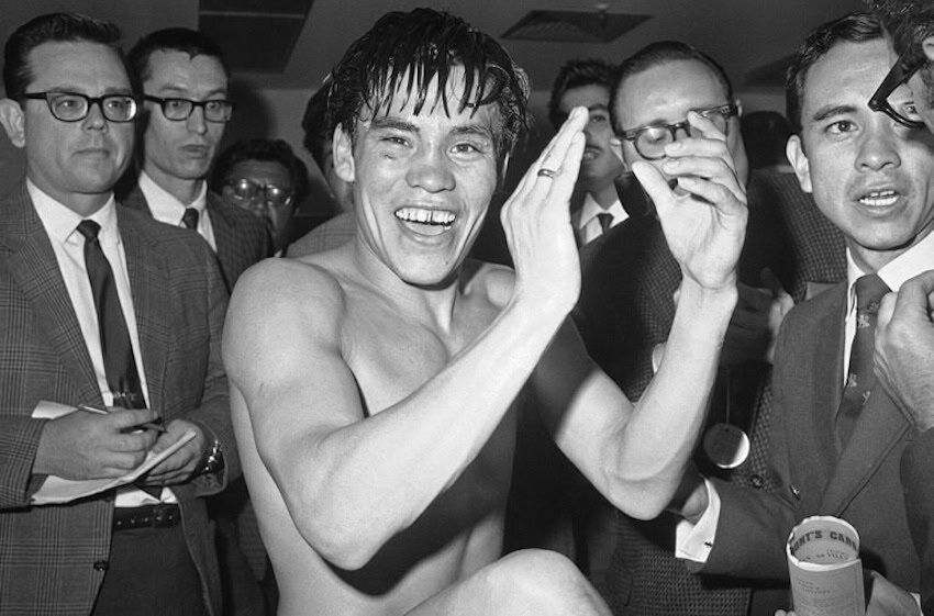 Rubén Olivares clapping in front of a group of suited men