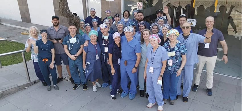 A group of doctors and volunteers poses for a photo outside a hospital