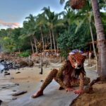 A woman in jaguar mask sitting on a beach