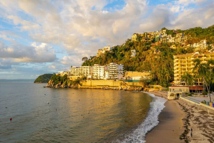 Coastal view of a sandy beach with resorts and hillside homes in Puerto Vallarta, Mexico.