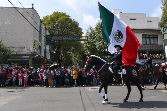 A military rider on horseback bears a Mexico flag in a parade