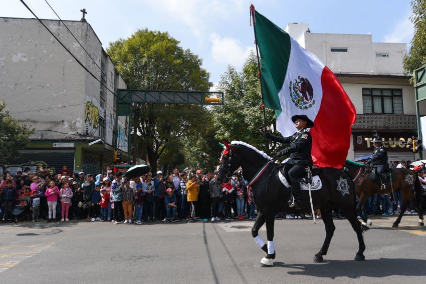 A military rider on horseback bears a Mexico flag in a parade
