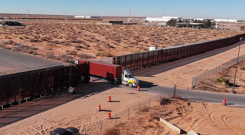 A semi truck crosses through a gate along the US-Mexico border
