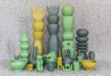 How a Mexico City studio is championing truly fair artisan partnerships A collection of unique, handcrafted Mexican ceramic art pieces in shades of green and yellow, including tall stacked sculptures, vases, bowls, and whimsical figures, arranged on a textured grey surface.