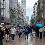 An unusually rainy June brings drought relief and flooding to Mexico people walk through mexico city with umbrellas, with the latin america tower in the backgound