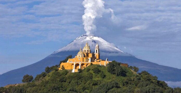 Nuestra Señora de los Remedios church in Cholula, Puebla, with Popocatépetl volcano smoking behind