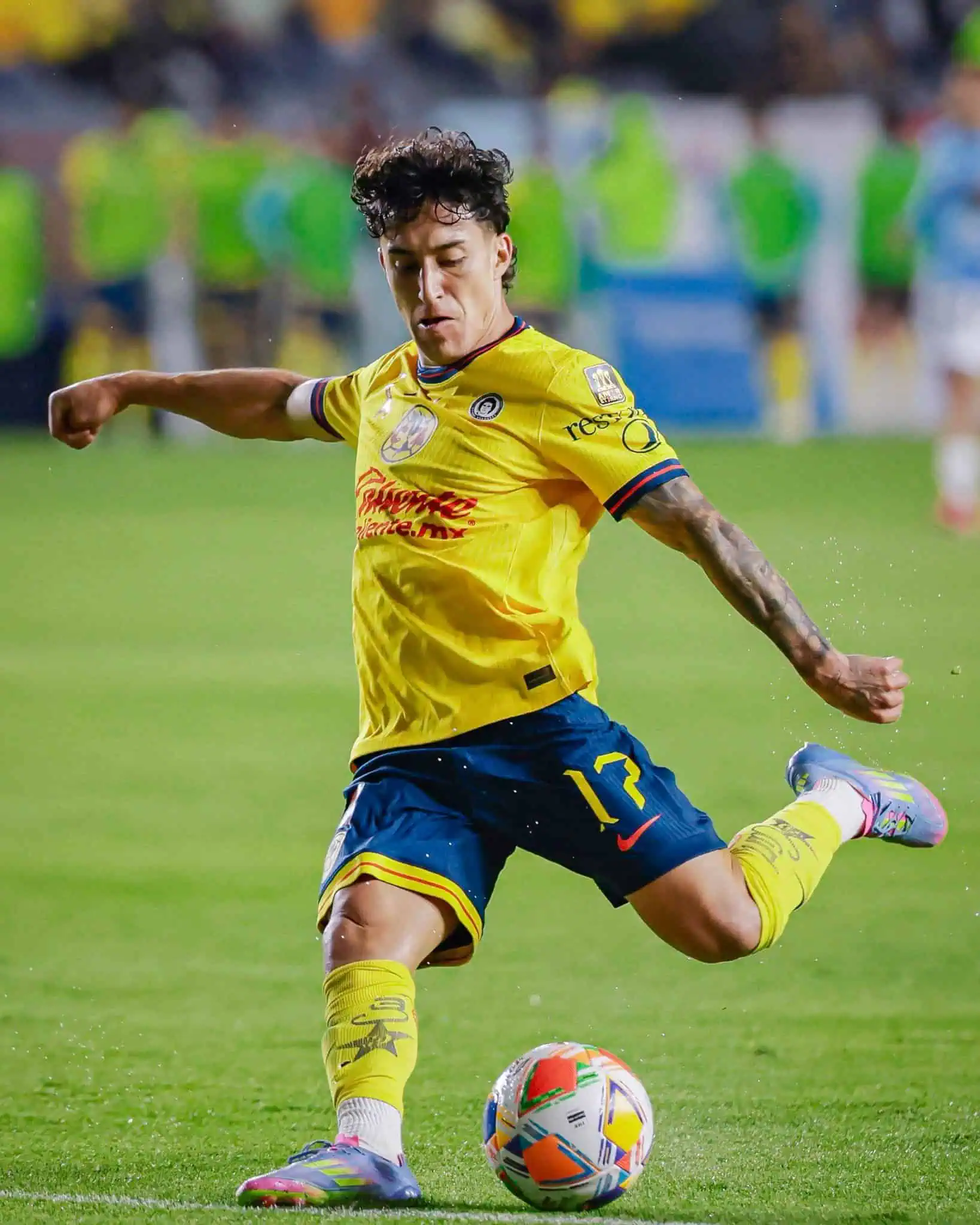 A player on the Mexico City soccer team Club America in uniform, gearing up to kick the ball in play during a game.