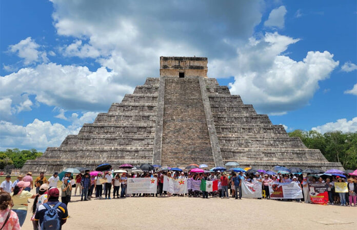 Teachers with protest signs and flags gather at the base of the Chichén Itzá pyramid