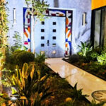 A touch of Frank Lloyd Wright in San Miguel de Allende A modern Mexican courtyard with parquet floor and stone double entrance doors to a home. The three sides around the doors feature modernist abstract colors of stained glass.