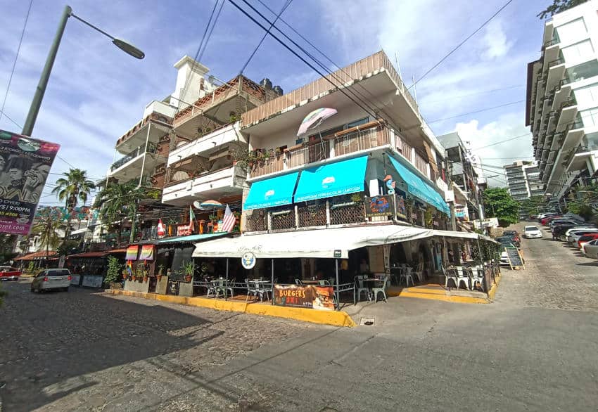 Corner building with restaurants and apartments on a sunny street in Puerto Vallarta, Mexico.