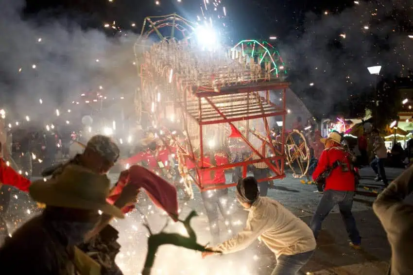 Sparks fly from a "torito," a bull-shaped fireworks contraption worn by participants in La Xiqueñada's evening celebrations in Xico's streets. Other participants dodge the sparks.