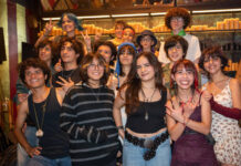 Retirement mecca San Miguel de Allende changes its tune with increasing youth activities A diverse group of smiling Mexican teenagers, with various hairstyles and clothing styles, pose for a group photo in a dimly lit restaurant or bar with rows of candles in the background.