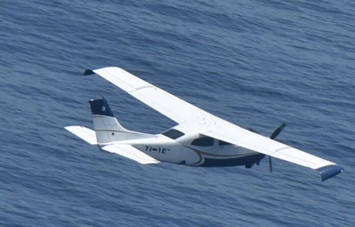 A small plane flies over the ocean