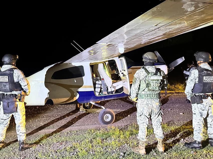 Mexican National Guard troops stand around a small airplane at night