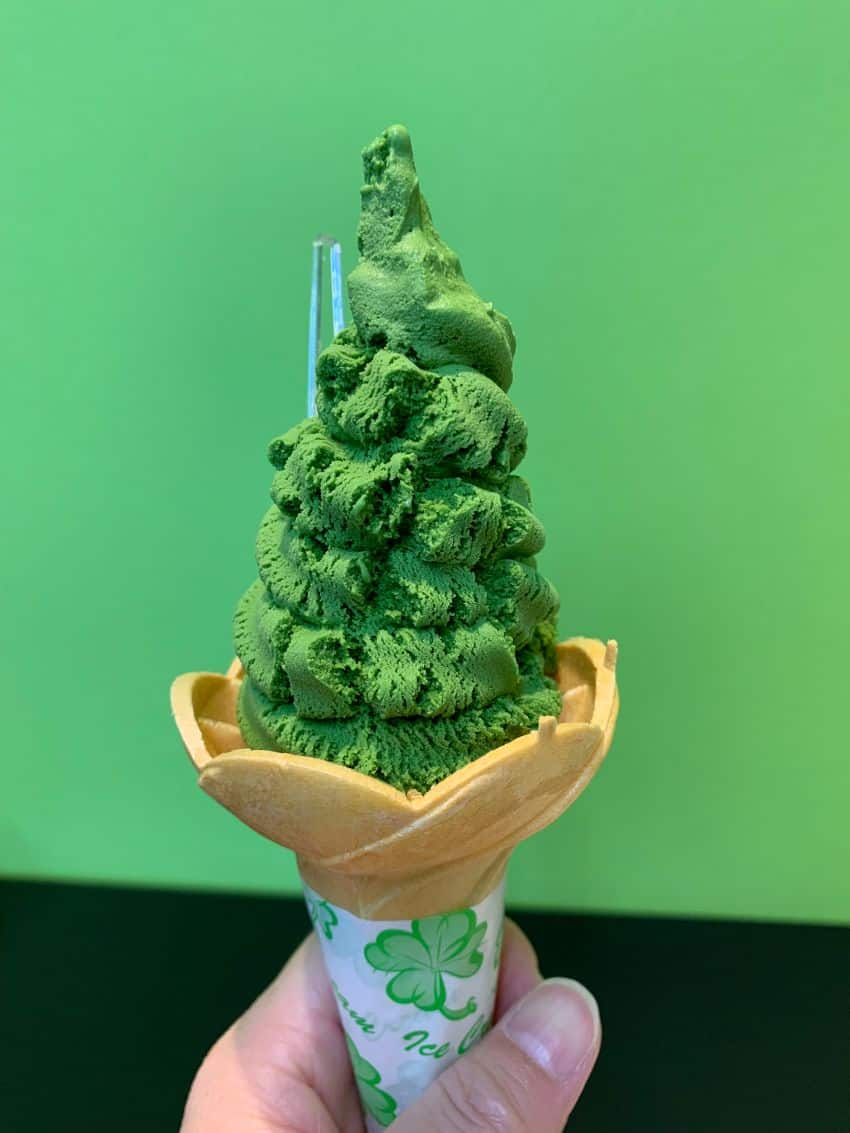 Dark green avocado ice cream piled high in a small ice cream cone