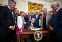 Trump signs a bill surrounded by supporters