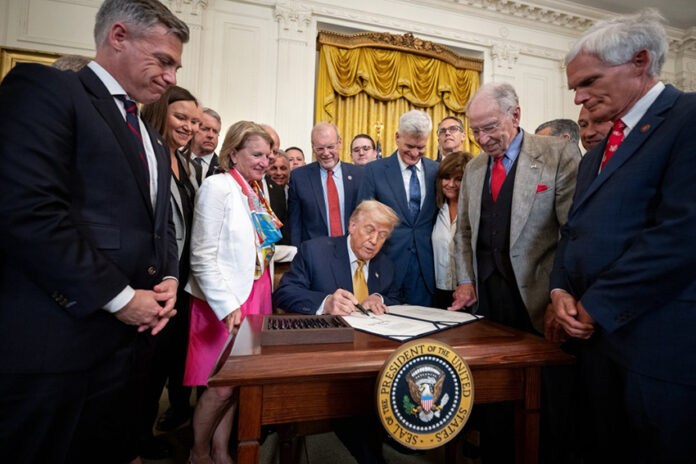 Trump signs a bill surrounded by supporters