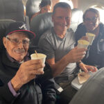 Travis and Tamanna Bembenek raise styrofoam cups to toast with Luis, an elderly Mexican man, on a plane