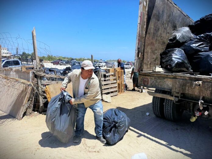 Sanitation worker hoists garbage bags into truck in Los Cabos