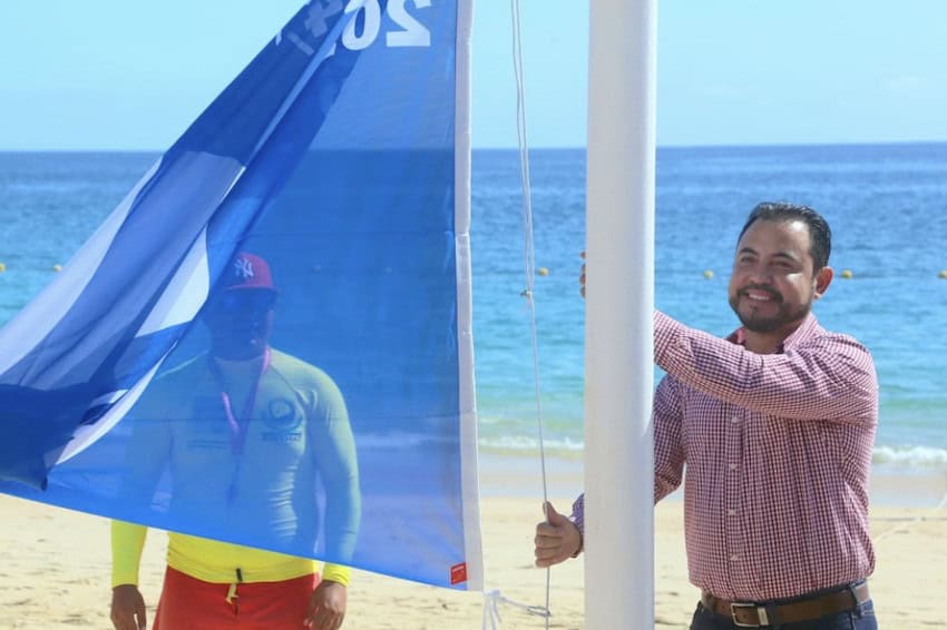 A man raising a blue flag on a Los Cabos beach