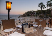 What’s on in Los Cabos in August? A reserved table at an outdoor restaurant overlooks a beach and ocean at sunset in Los Cabos, Baja California Sur, Mexico