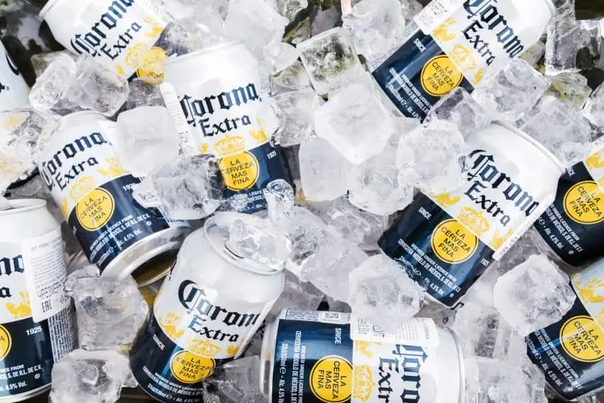 Cans of Cororna Extra beer lying on a bed of large ice cubes