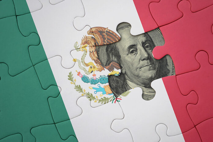 A United States dollar bill peeks out from behind a Mexican flag puzzle