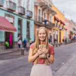 A blond woman holds churros in a Mexican street