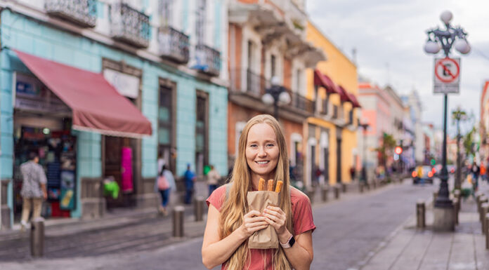 A blond woman holds churros in a Mexican street