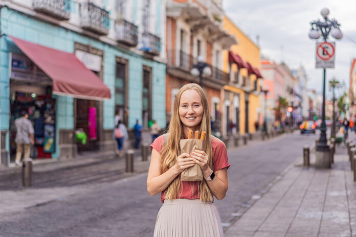A blond woman holds churros in a Mexican street