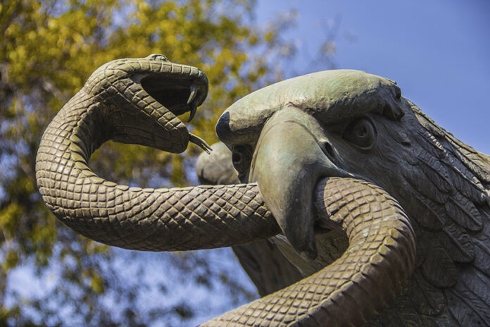 A sculpture depicts an eagle devouring a snake atop a nopal cactus, as seen on Mexico's national coat of arms.