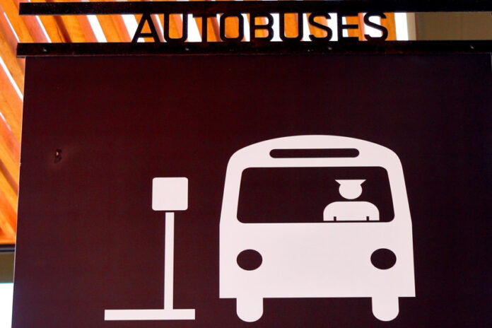 A sign in Puerto Vallarta indicating a bus hub with a icon of a man driving a bus pulling up to a bus stop sign and the word 