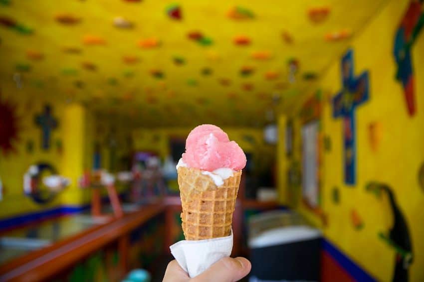 Pink ice cream in cone held by hand