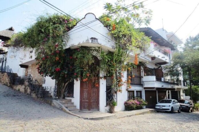 An adobe home with colonial-style carved wooden double doors ists on a street corner in downtown Puerto Vallarta