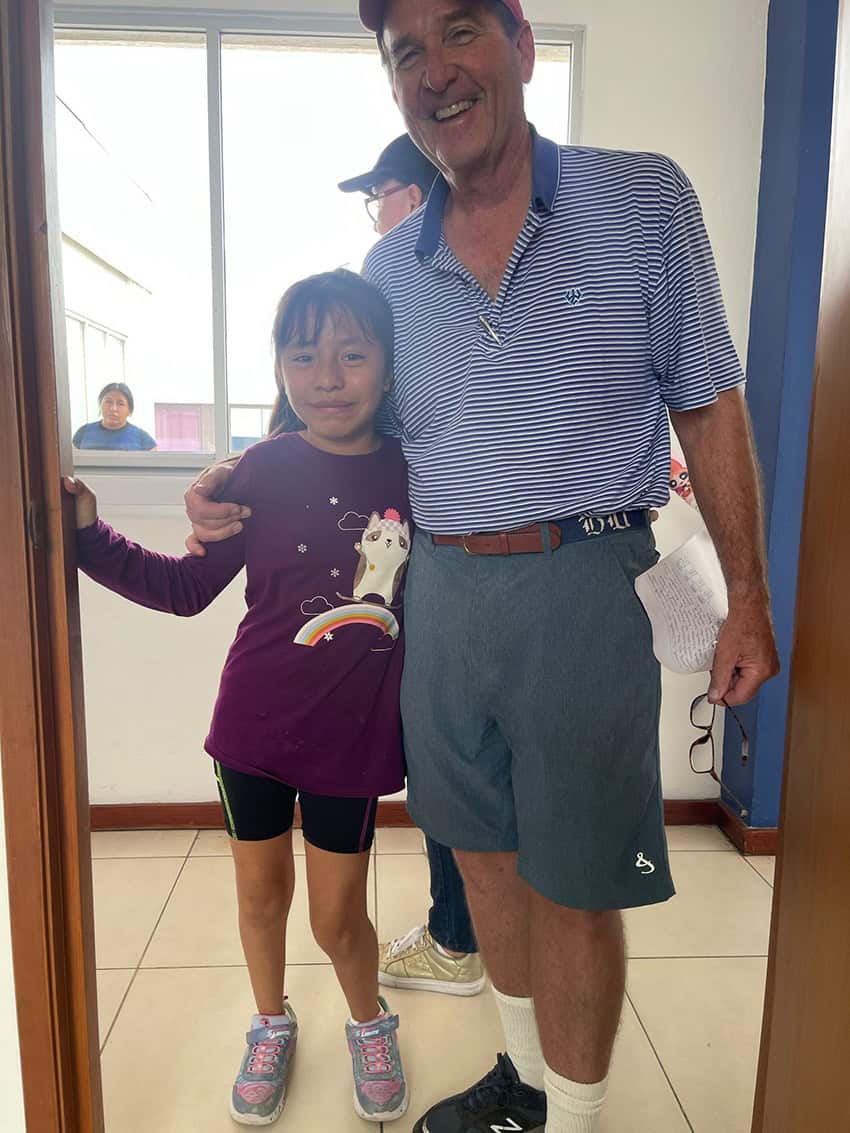 Dr. Billy Andrews, an middle-aged American man in shorts, poses with a young Mexican girl in a hospital