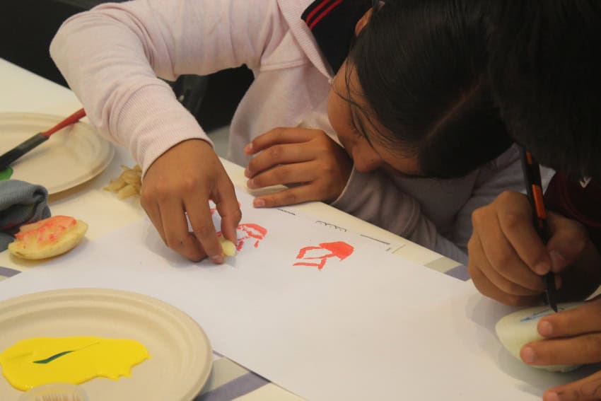 A Mexican child making block printed designs on white paper.