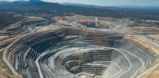 An large open-pit mine in an arid area with mountains in the background